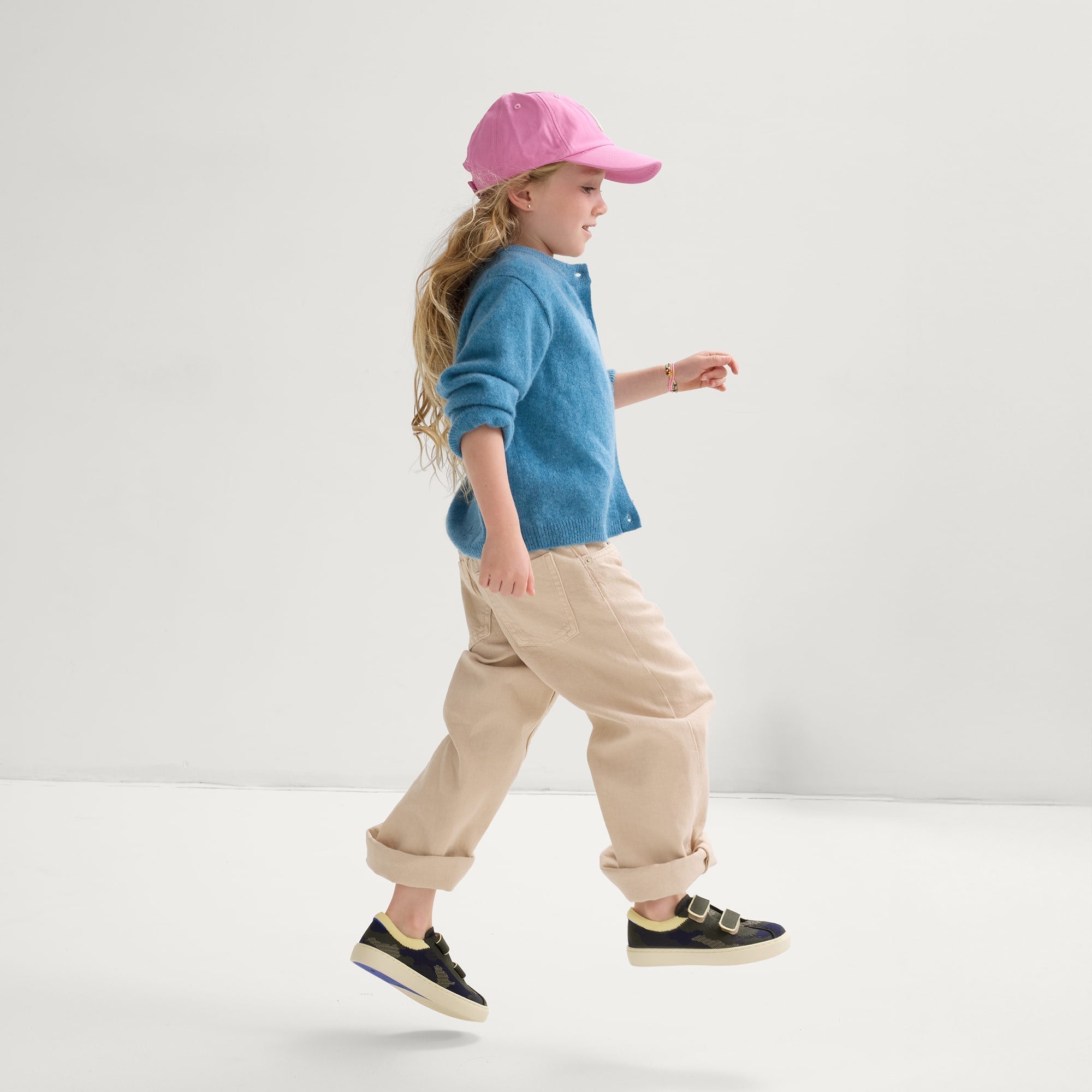 model | An alternate image of a child modeling The Kids Strap Sneaker in Spruce Camo. 