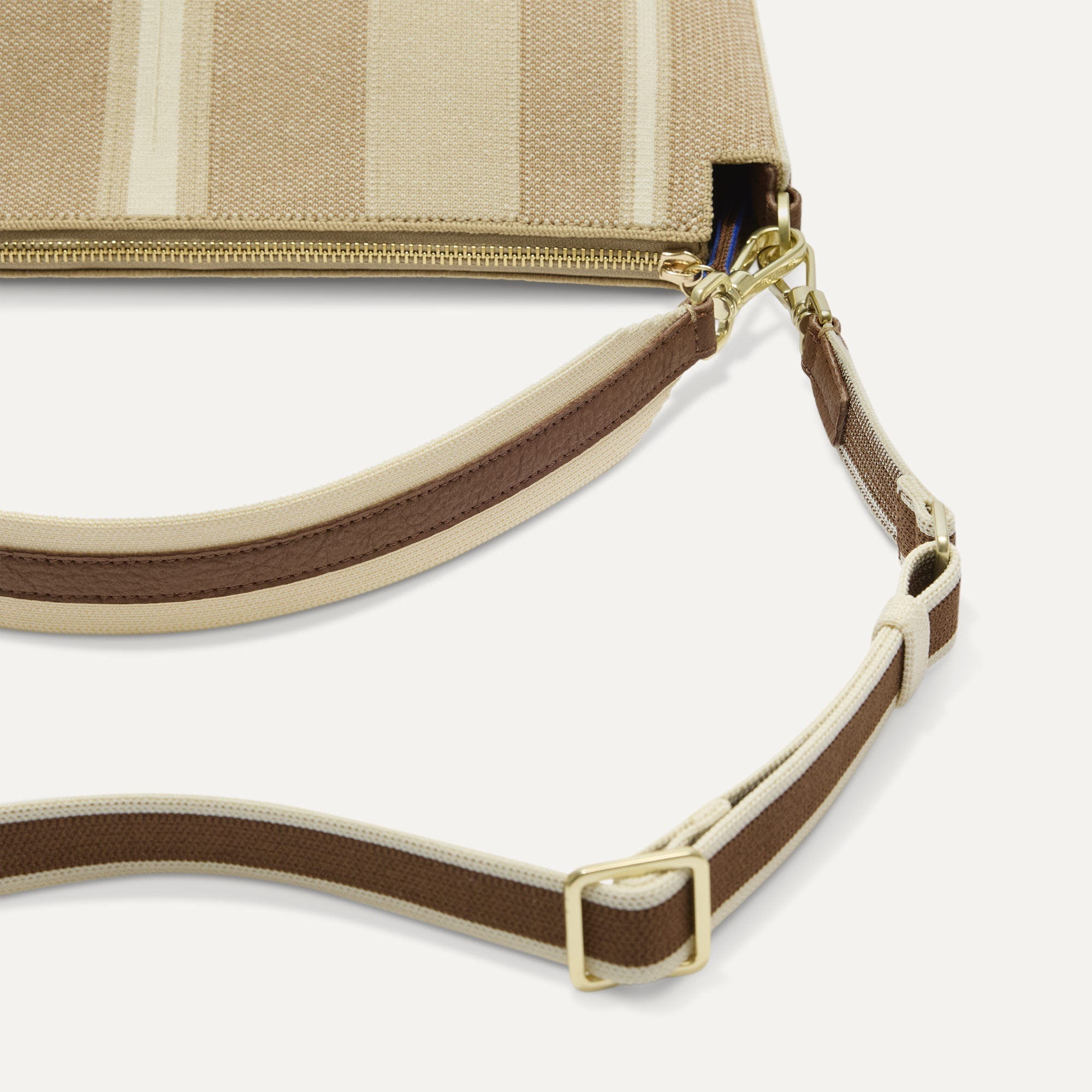 The Daily Crossbody in Oat Latte, lying flat, showing the detachable top handle and adjustable crossbody strap.