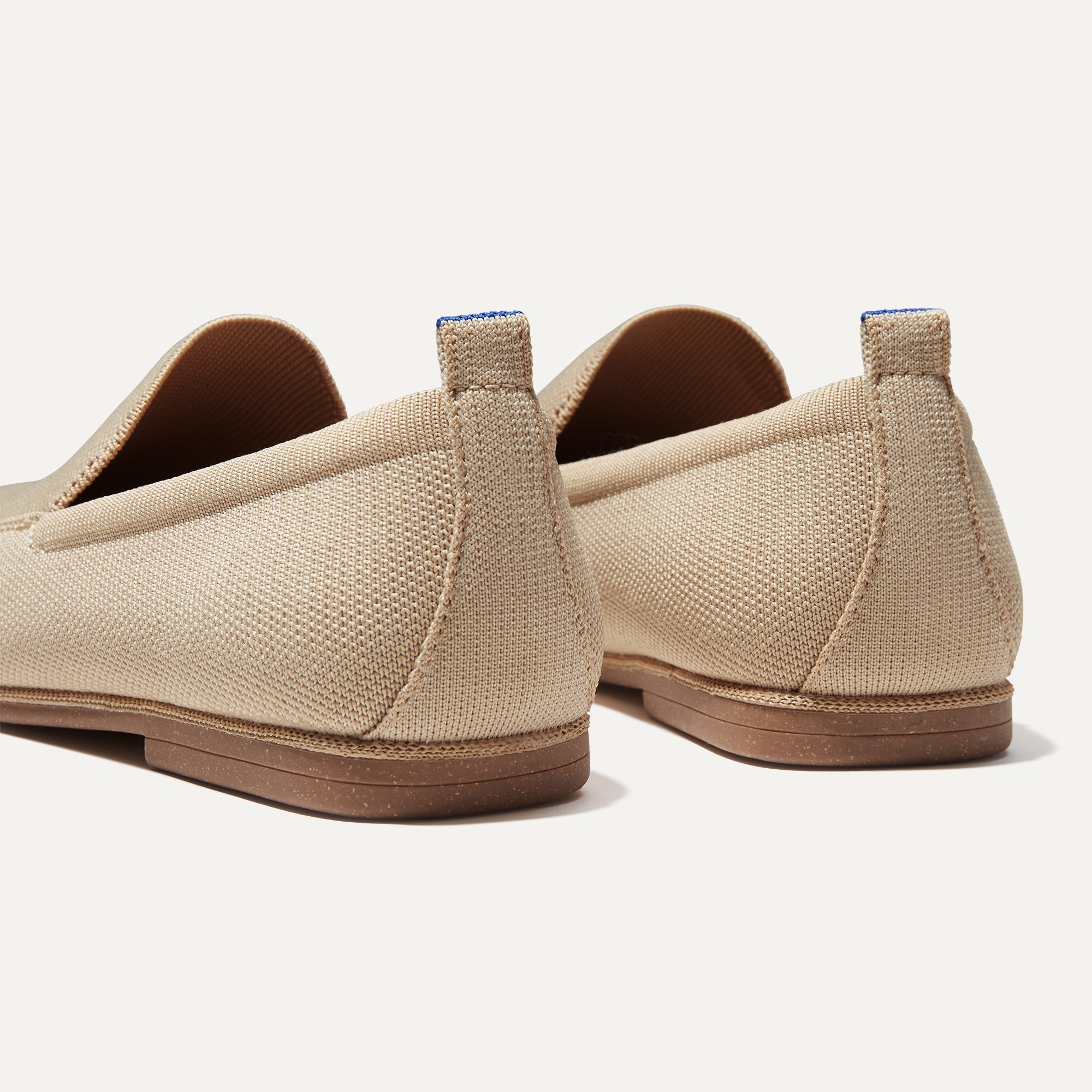 Close up of the heel of The Ravello Loafer in Sand, with Rothy's signature blue halo on the pull tab.