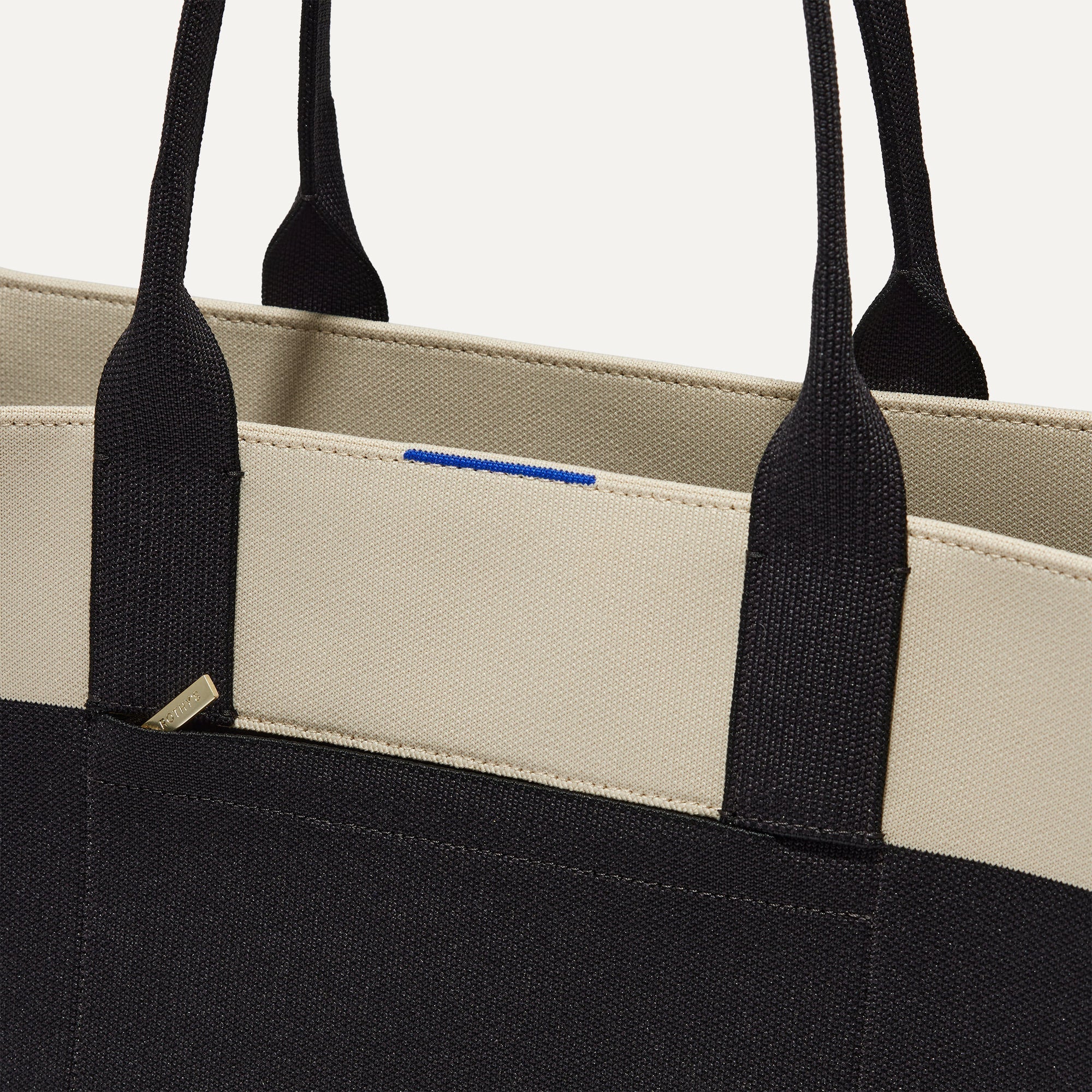 A closeup of The Classic Tote in Luna, focusing on the exterior zip pocket. 