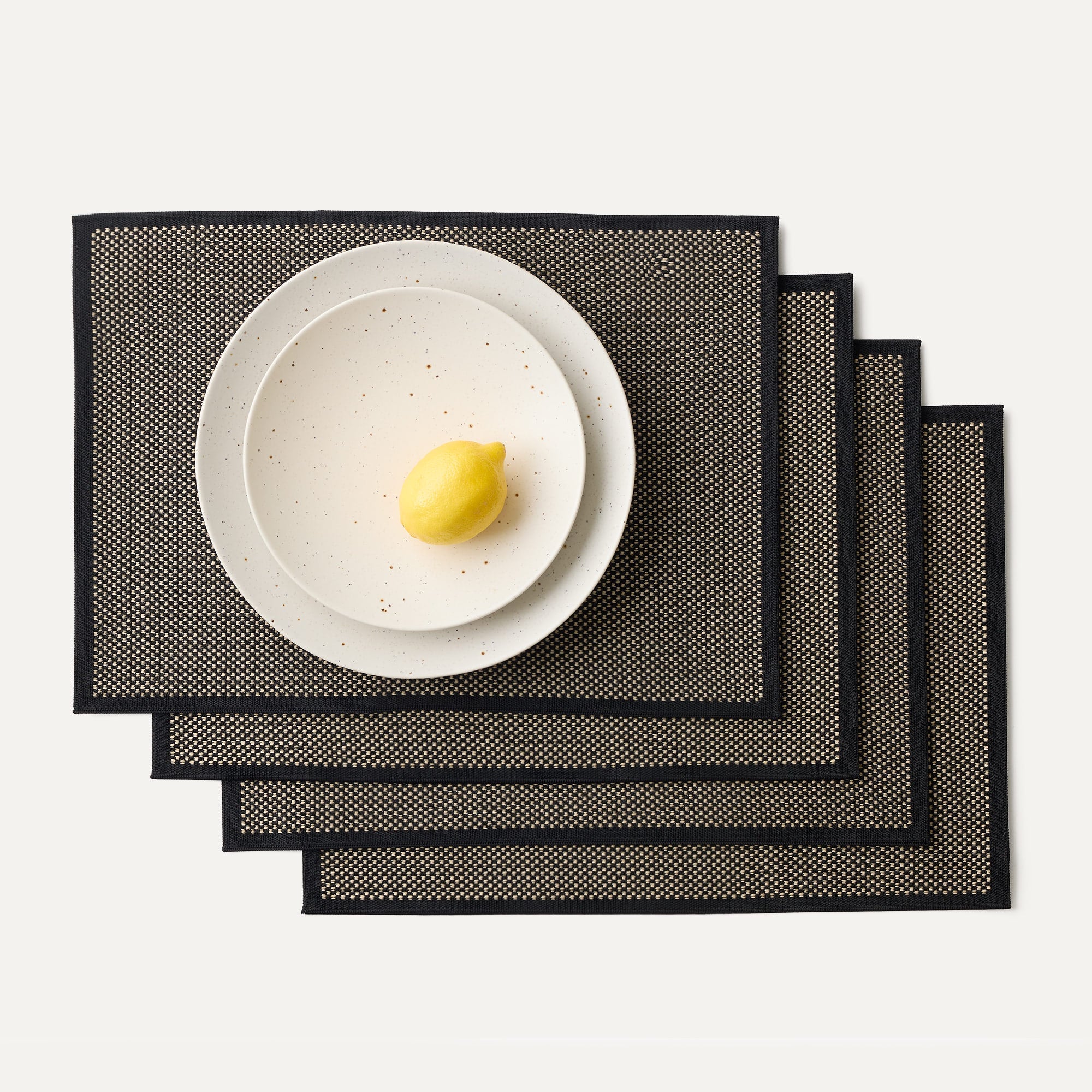 A set of four Placemats in Peppercorn shown with a plate setting.