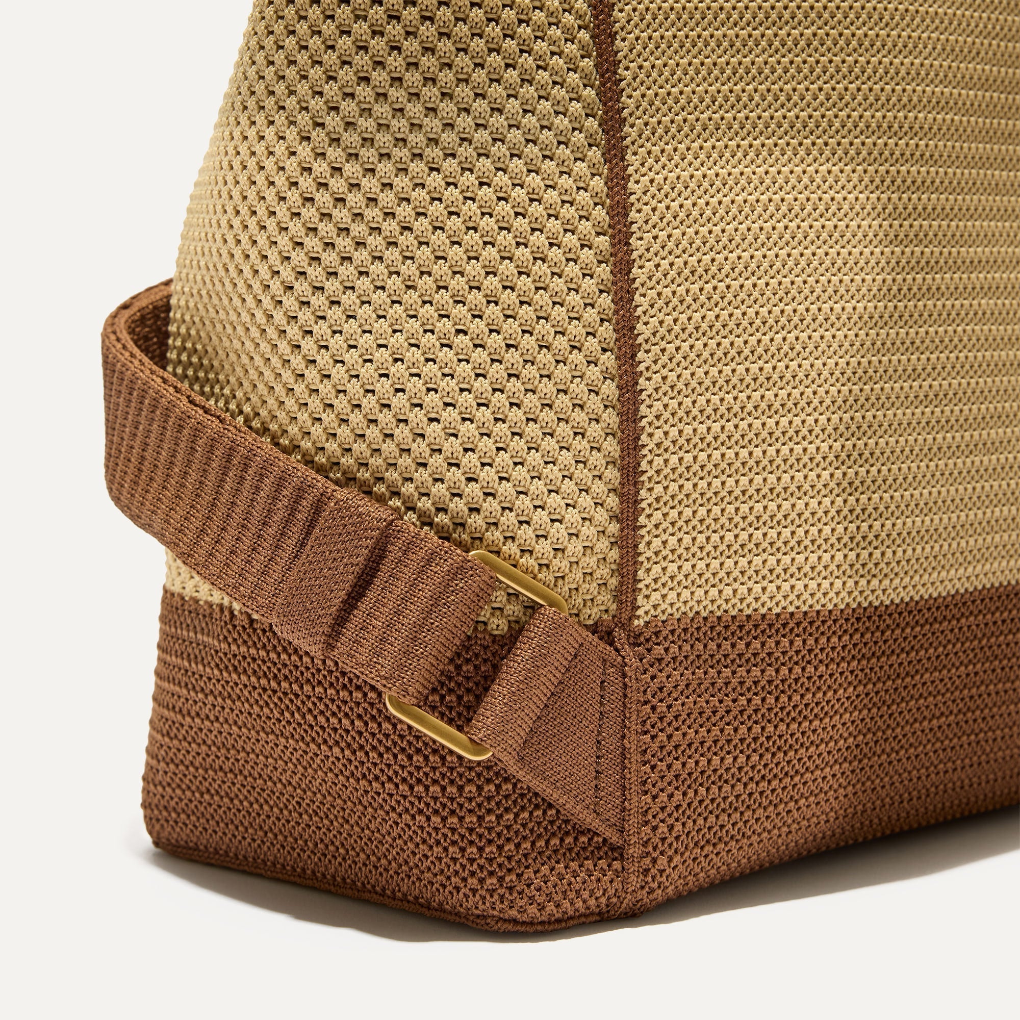 A close up of the The Cinch Backpack in Brown Butter focusing on the gold hardware on the straps.