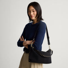 hover | The Daily Crossbody in Revelvet™ Black, carried over the shoulder of a female model, shown from the right.