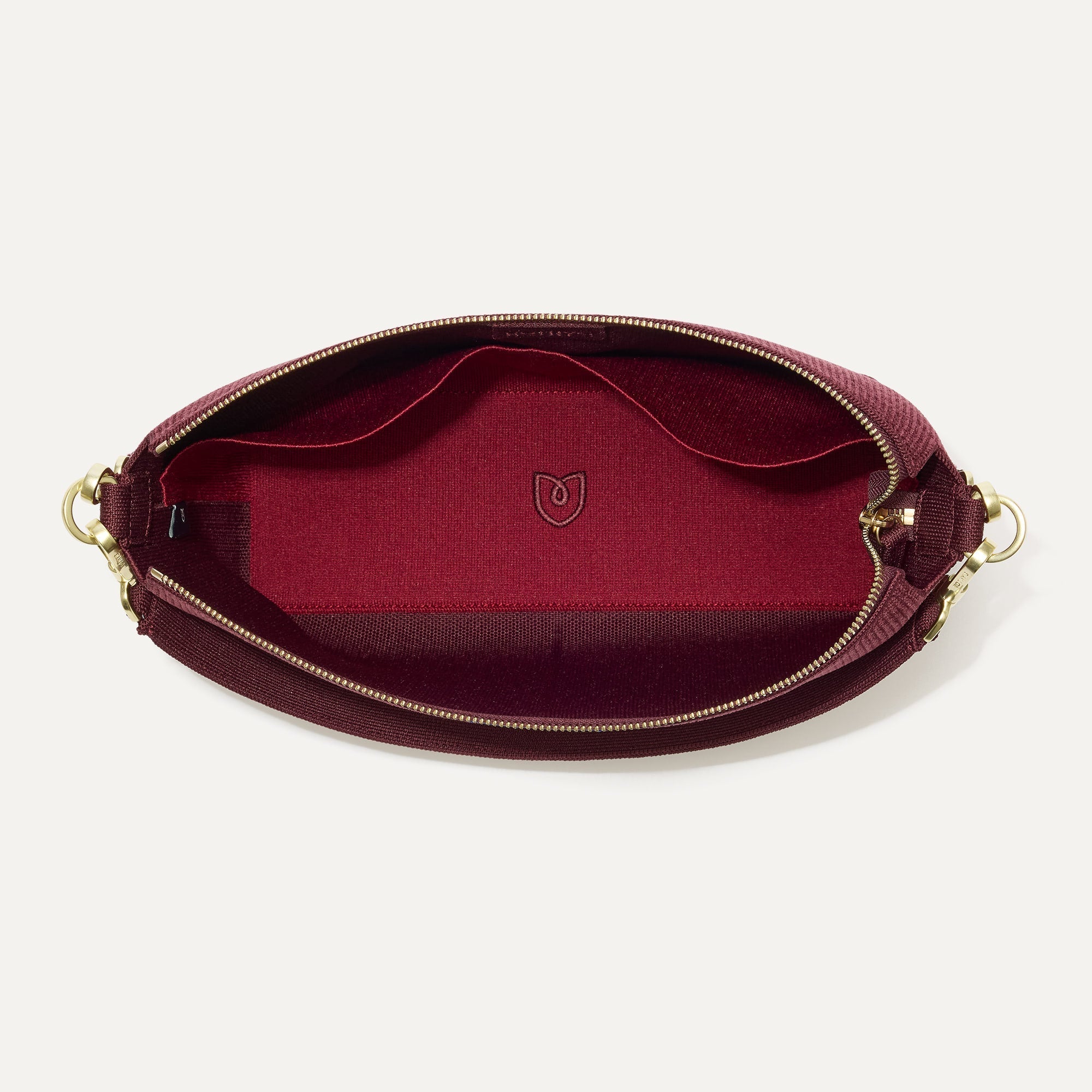 The Daily Crossbody in ReVelvet™ Syrah, shown from the top down, with zipper open and interior exposed.