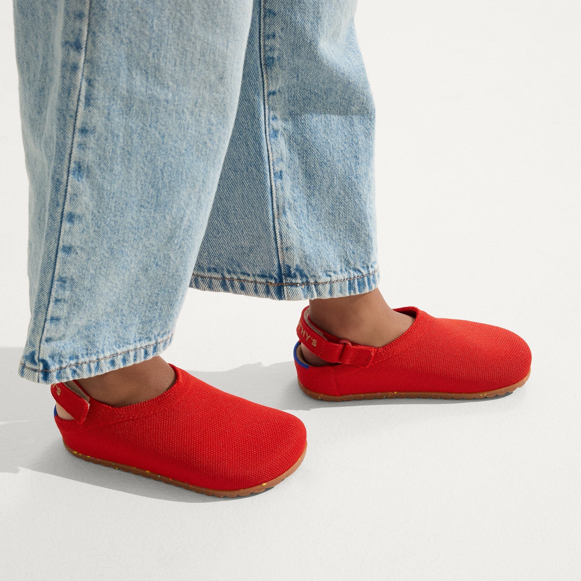 hover | A child wearing The Kids Clog in Firetruck Red. 