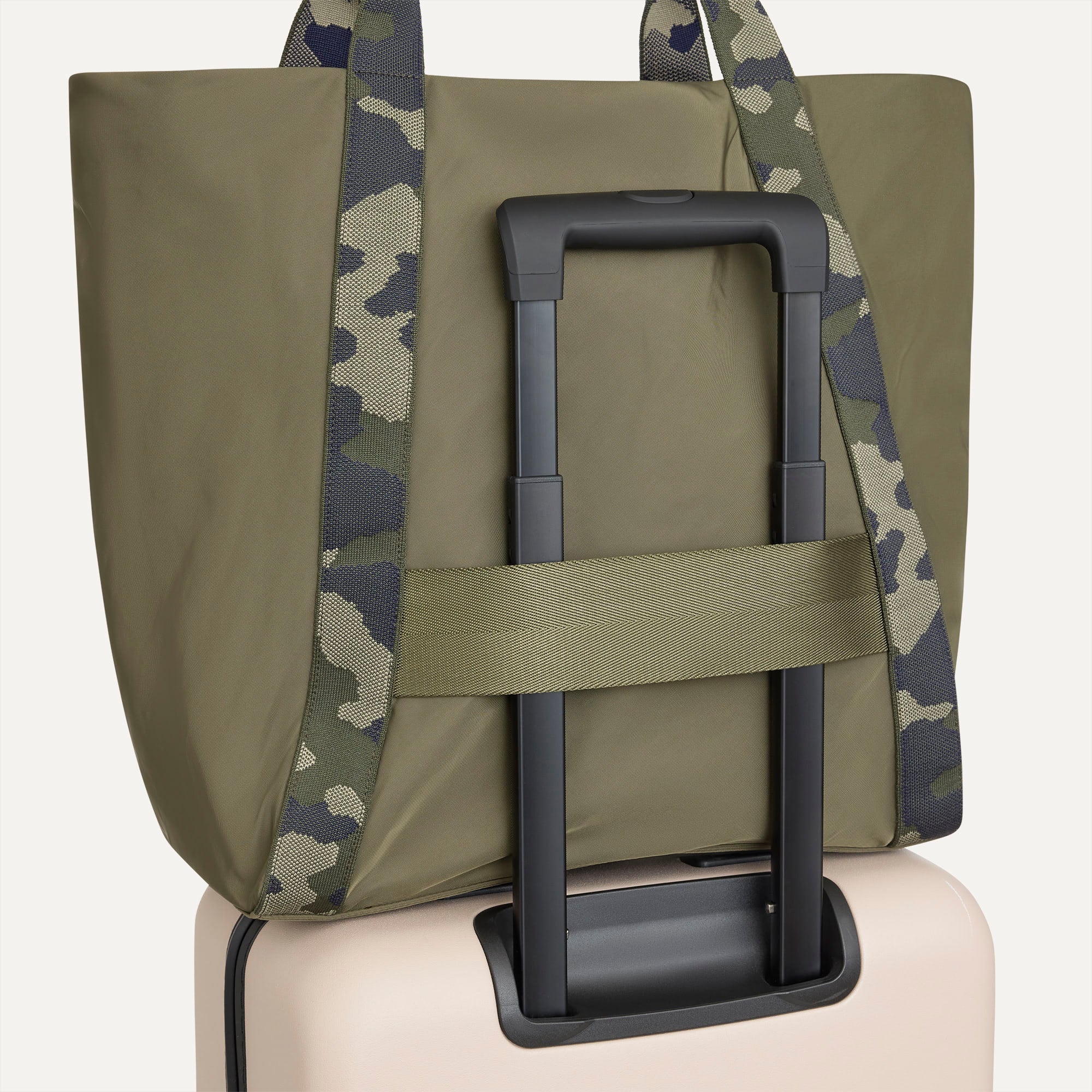 The Travel Tote in Forest, shown attached to a rolling suitcase using the wrap-around band.