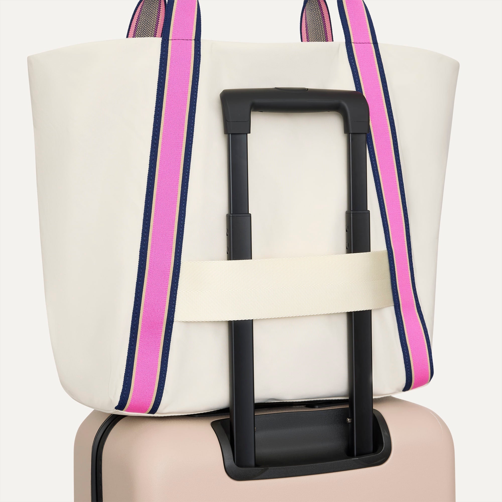 The Travel Tote in Optic, shown attached to a rolling suitcase using the wrap-around band.