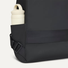 A close up of the The Travel Cinch Backpack in Ink focusing on the straps, and the side pocket.