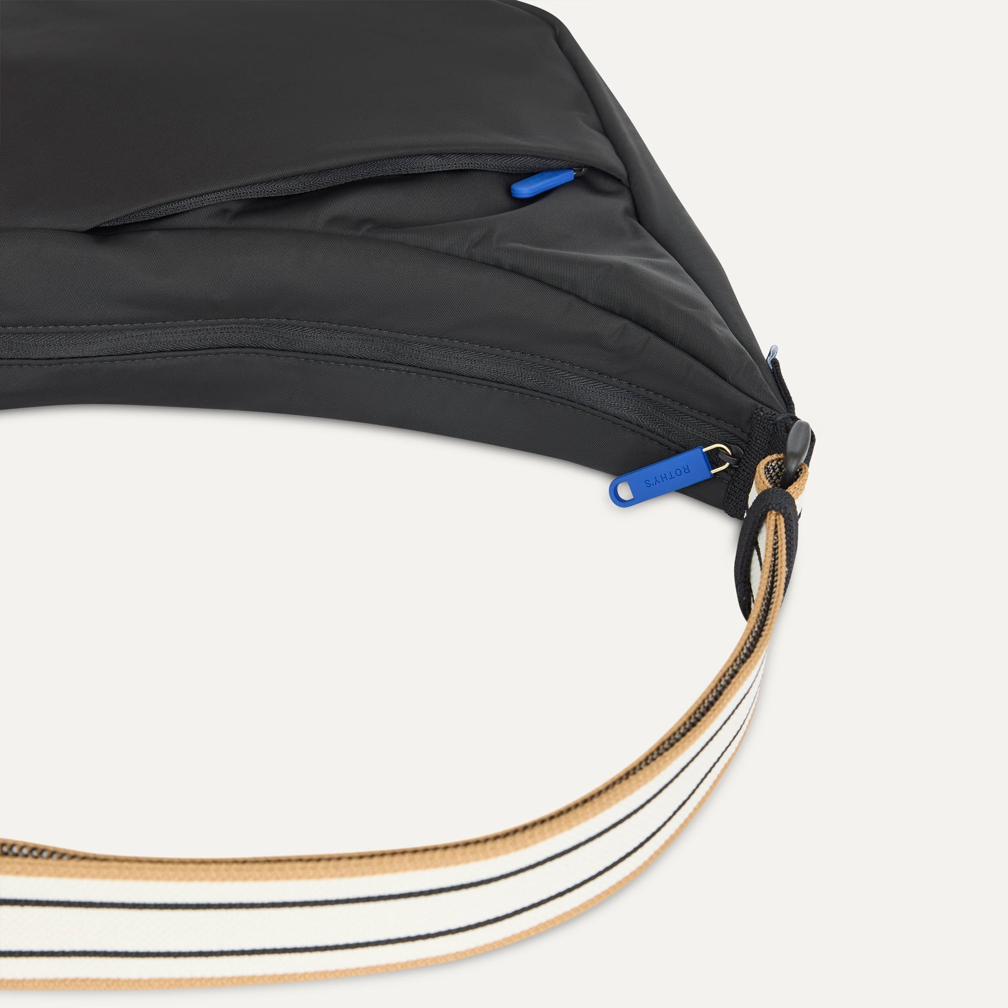 A closeup of The Travel Sling in Ink, showing the smooth zipper closure and soft, flexible handle.