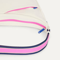 A closeup of The Travel Sling in Optic, showing the smooth zipper closure and soft, flexible handle.