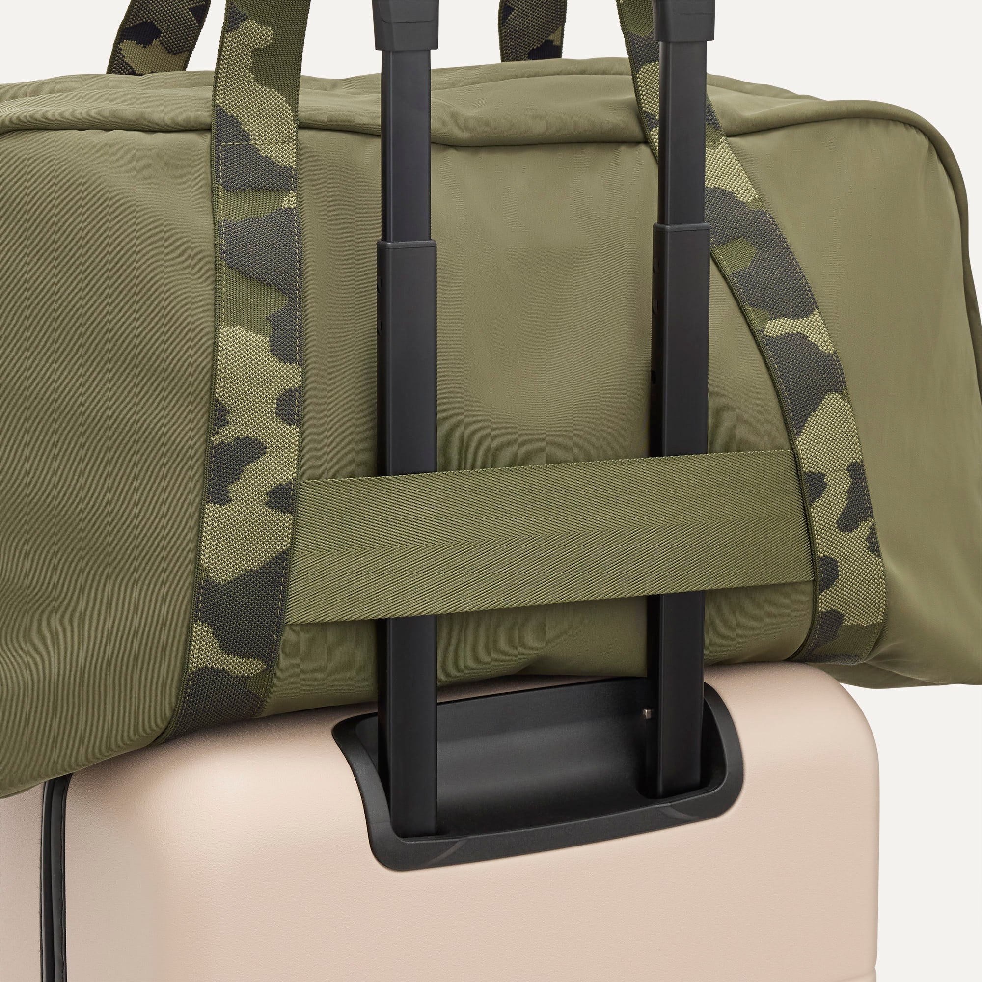 The Travel Duffle in Forest shown attached to a rolling suitcase using the wrap-around band.