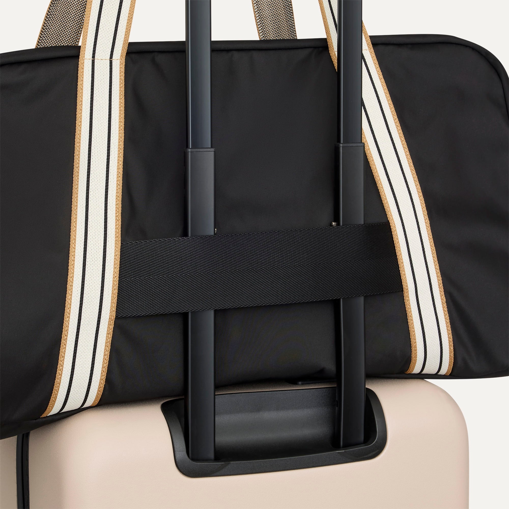 The Travel Duffle in Ink shown attached to a rolling suitcase using the wrap-around band.