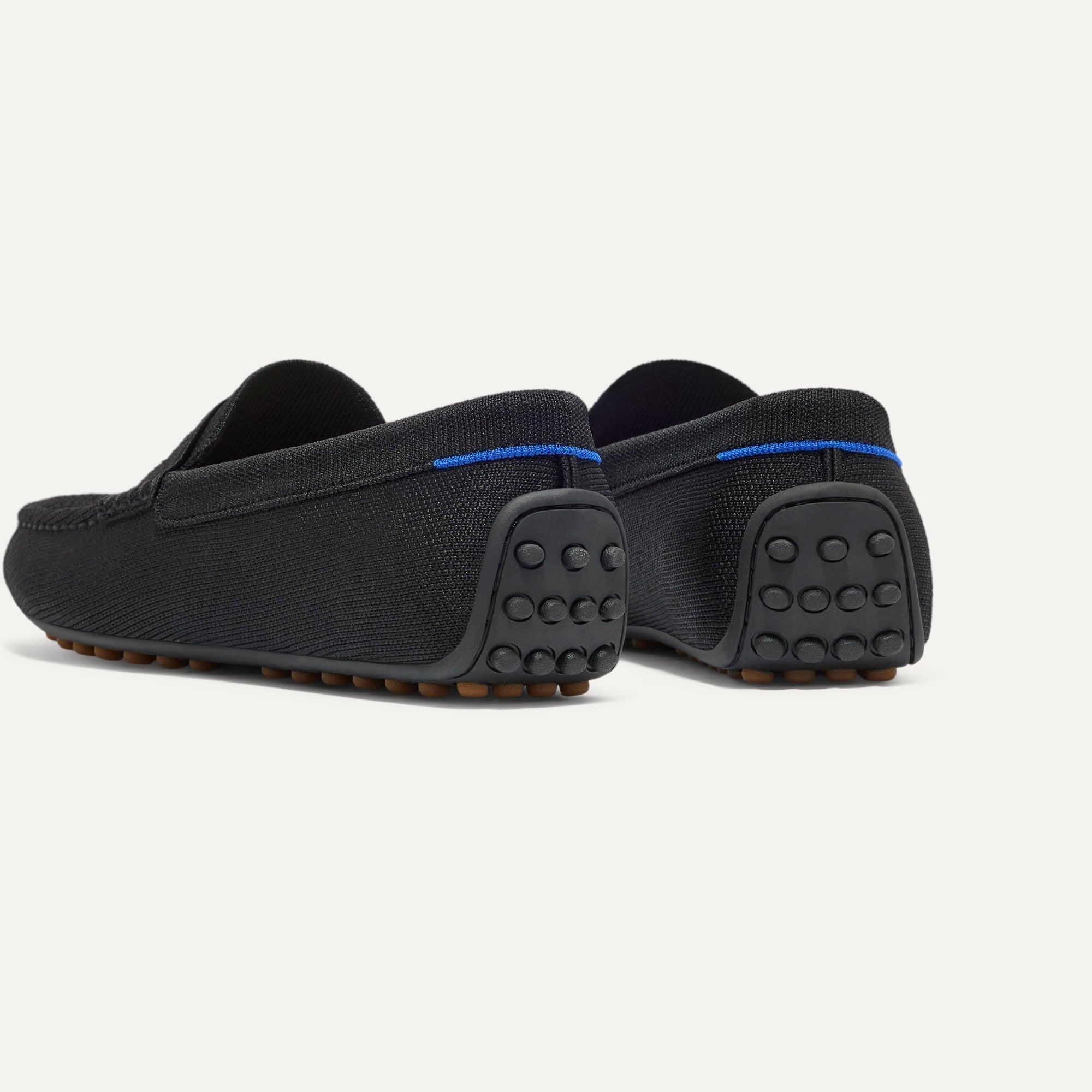 Close up of the heel of The Men's Daily Driver in Black, with raised peg outsoles and Rothy's signature blue halo. 