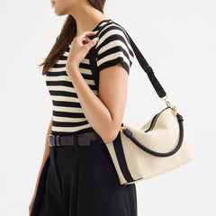 hover | The Daily Crossbody in Black and White Raffia-Knit, carried over the shoulder of a female model, shown from the right.
