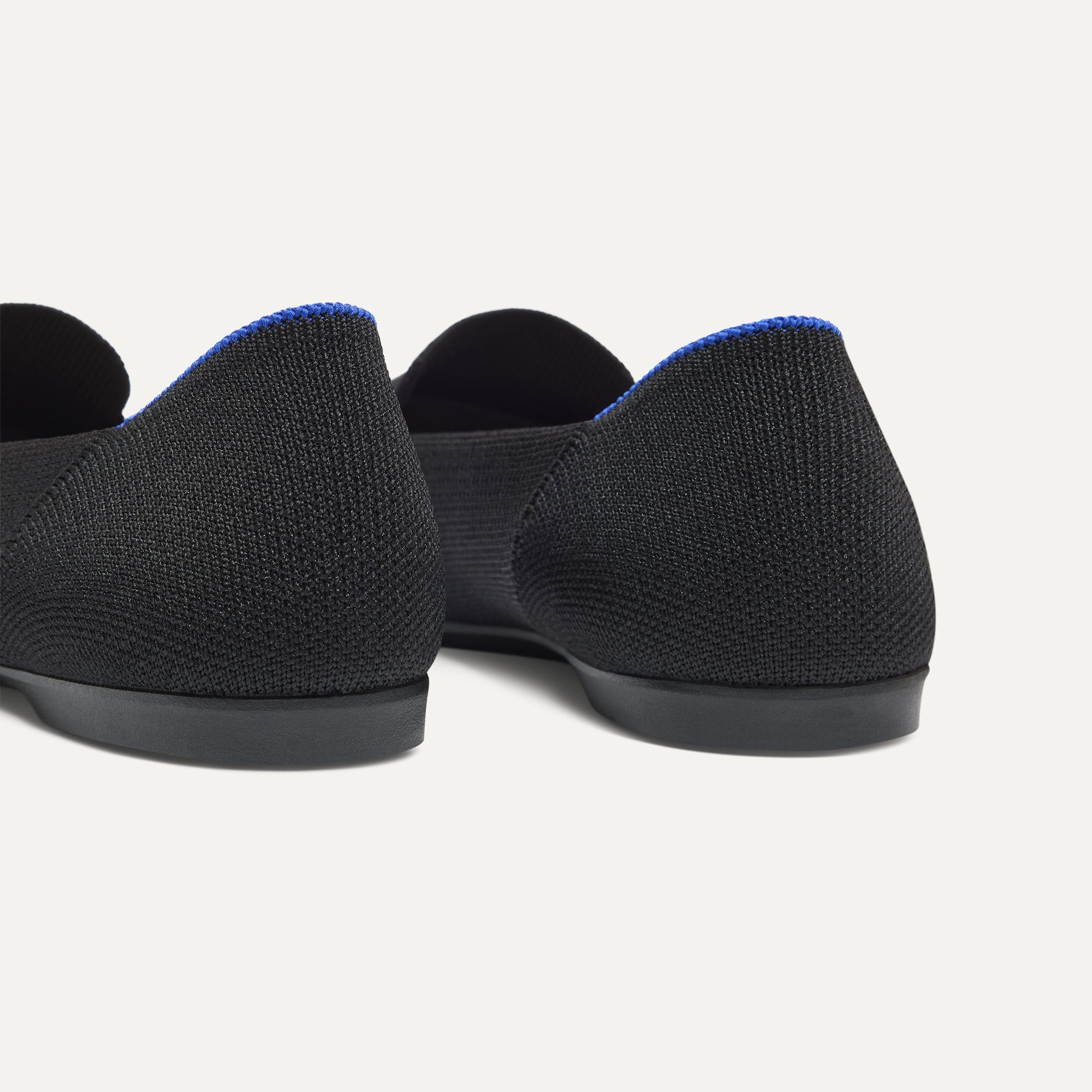 Close up of the heel of The Daily Loafer in Black, with raised peg outsoles and Rothy's signature blue halo. 