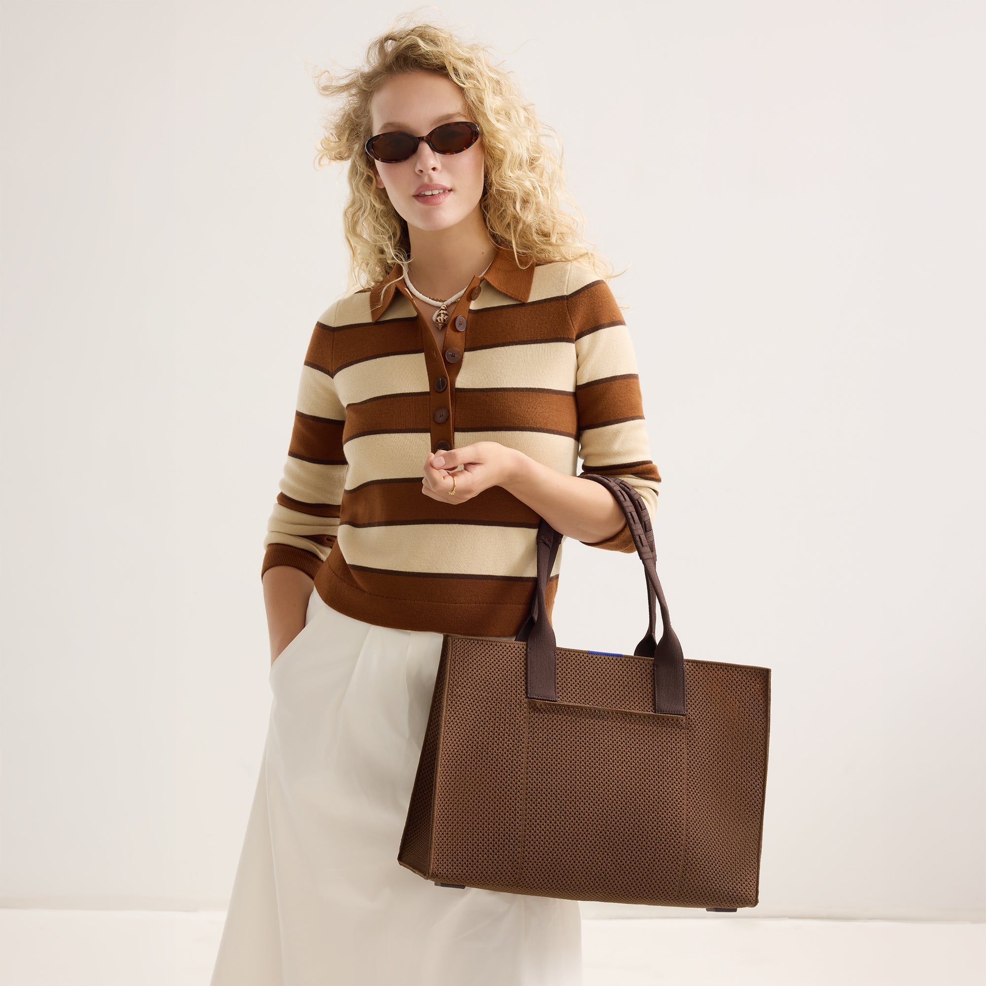 hover | The Classic Tote in Cinnamon Open Knit, carried by its top handles by a model, shown from the front.