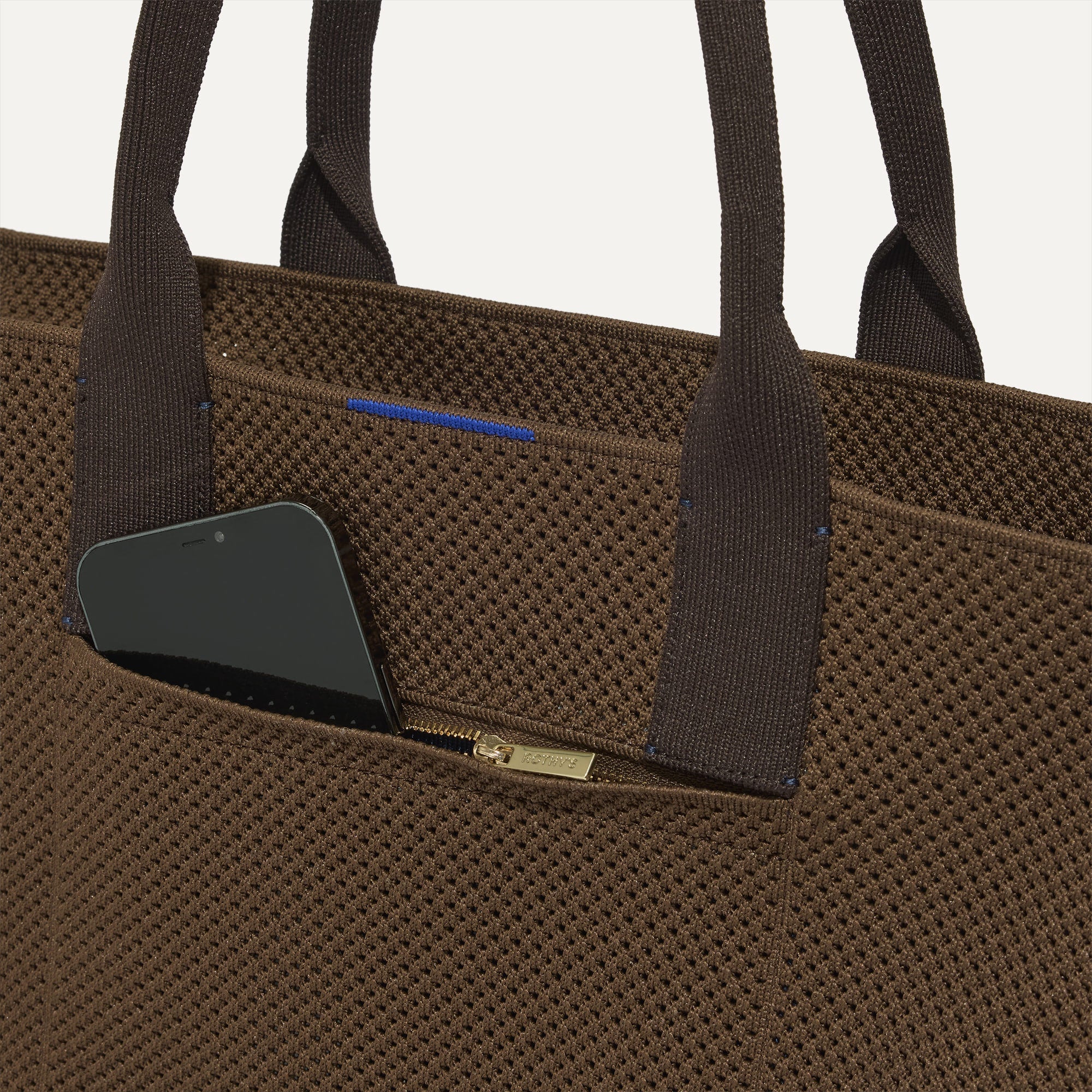 A closeup of The Classic Tote in Cinnamon Open Knit, focusing on the exterior zip pocket. 