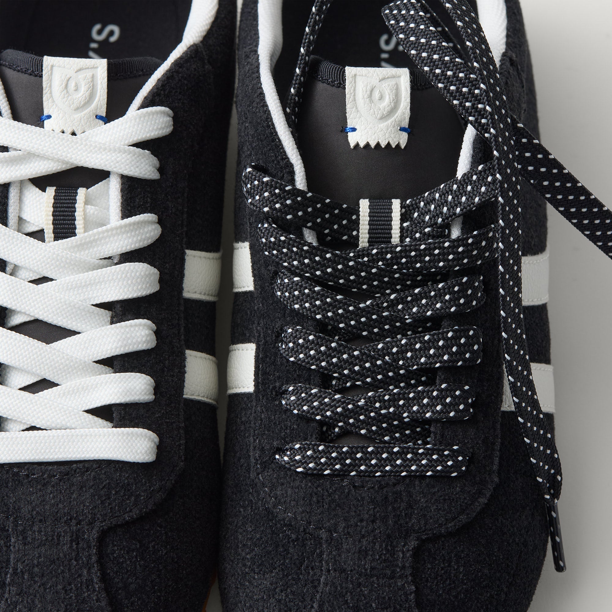 Overlay:: Extra pair of laces included—swap for a new look anytime. | Alt:: Close up of the top of The Ivy Sneaker in ReVelvet Black, showing different lace choices.
